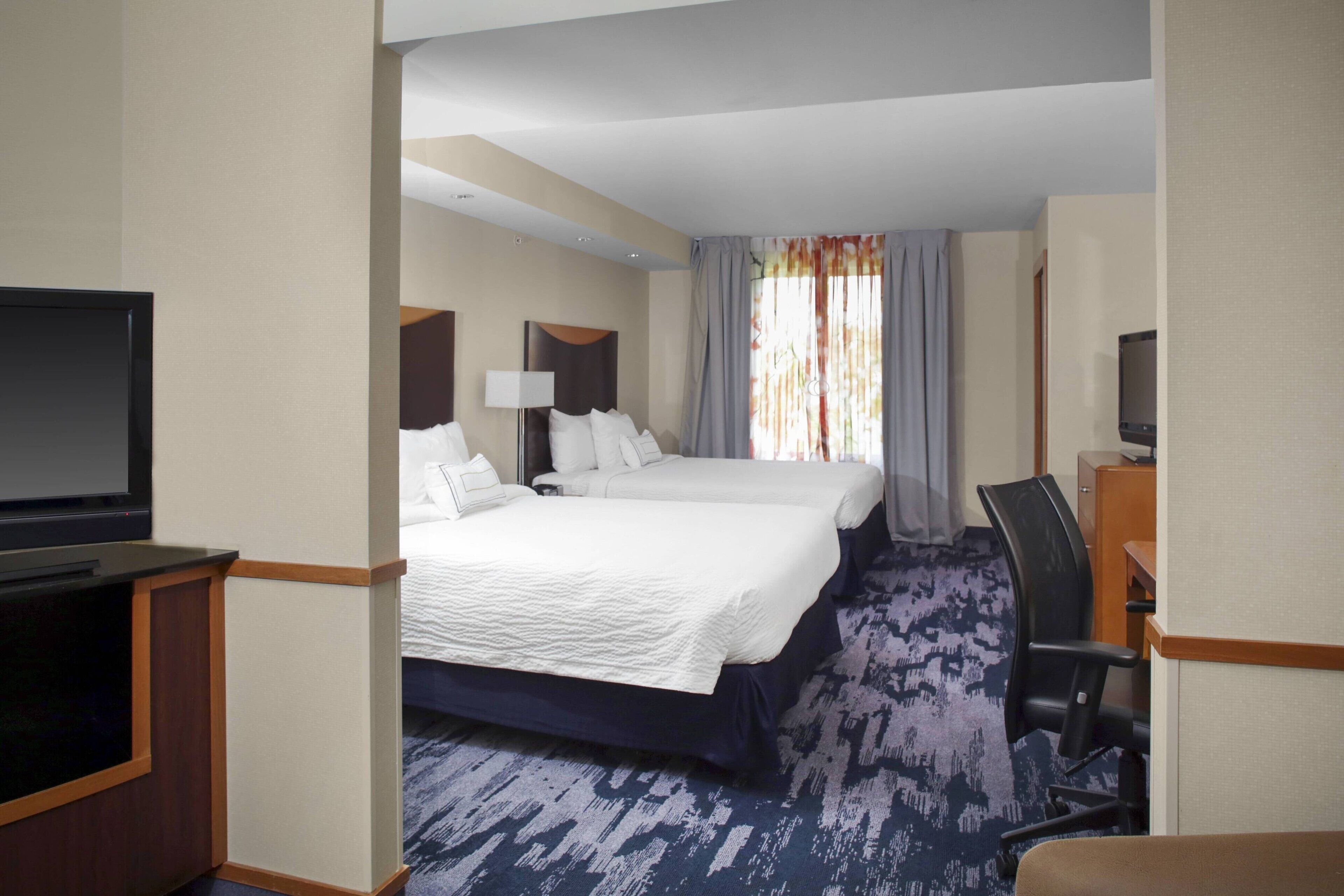Una habitación de hotel con una cama grande, un escritorio, una silla y un televisor.