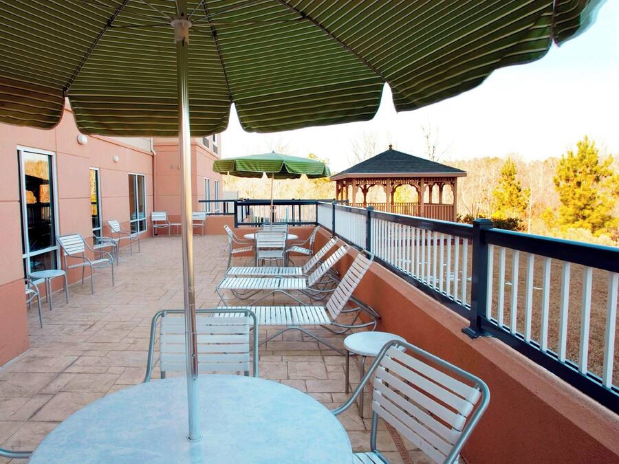 An outdoor patio with metal chairs and tables, a gazebo, and a covered area with umbrellas.