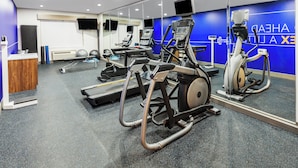 A modern gym with cardio machines, mirrors, and a reception desk. - Holiday Inn Express and Suites Henderson by IHG (Henderson)