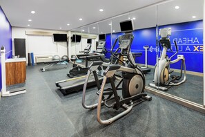 Un gimnasio moderno con máquinas de cardio, espejos y un mostrador de recepción.