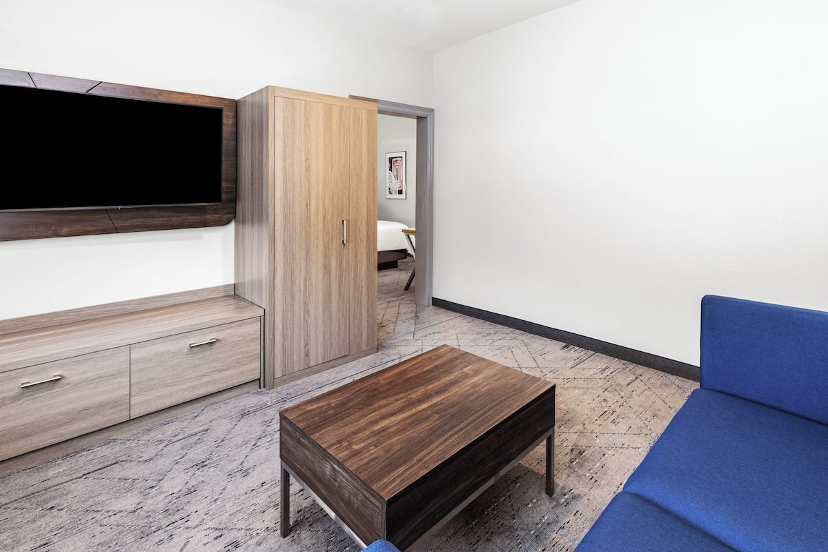 Ein modernes Zimmer mit Flachbildfernseher, Holzschrank und blauem Sofa.
