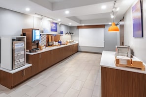 A modern kitchen with a yogurt dispenser, eggs, and milk station, wooden cabinets, and a white countertop. - Holiday Inn Express and Suites Henderson by IHG (Henderson)