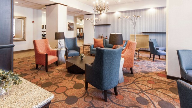 A lobby with seating areas, a chandelier, and a patterned carpet. - Hampton Inn & Suites Huntsville Hampton Cove (Brownsboro)