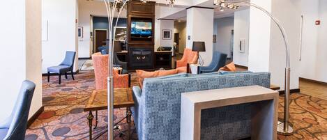 A hotel lobby with seating areas, a television, and a chandelier.