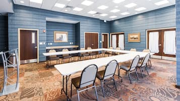 A conference room with a long table, chairs, and patterned carpet.