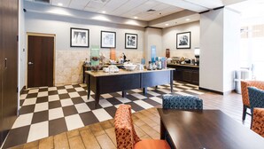 A hotel lobby with a checkered floor, a reception desk, seating area, and framed pictures on the wall. - Hampton Inn & Suites Huntsville Hampton Cove (Brownsboro)