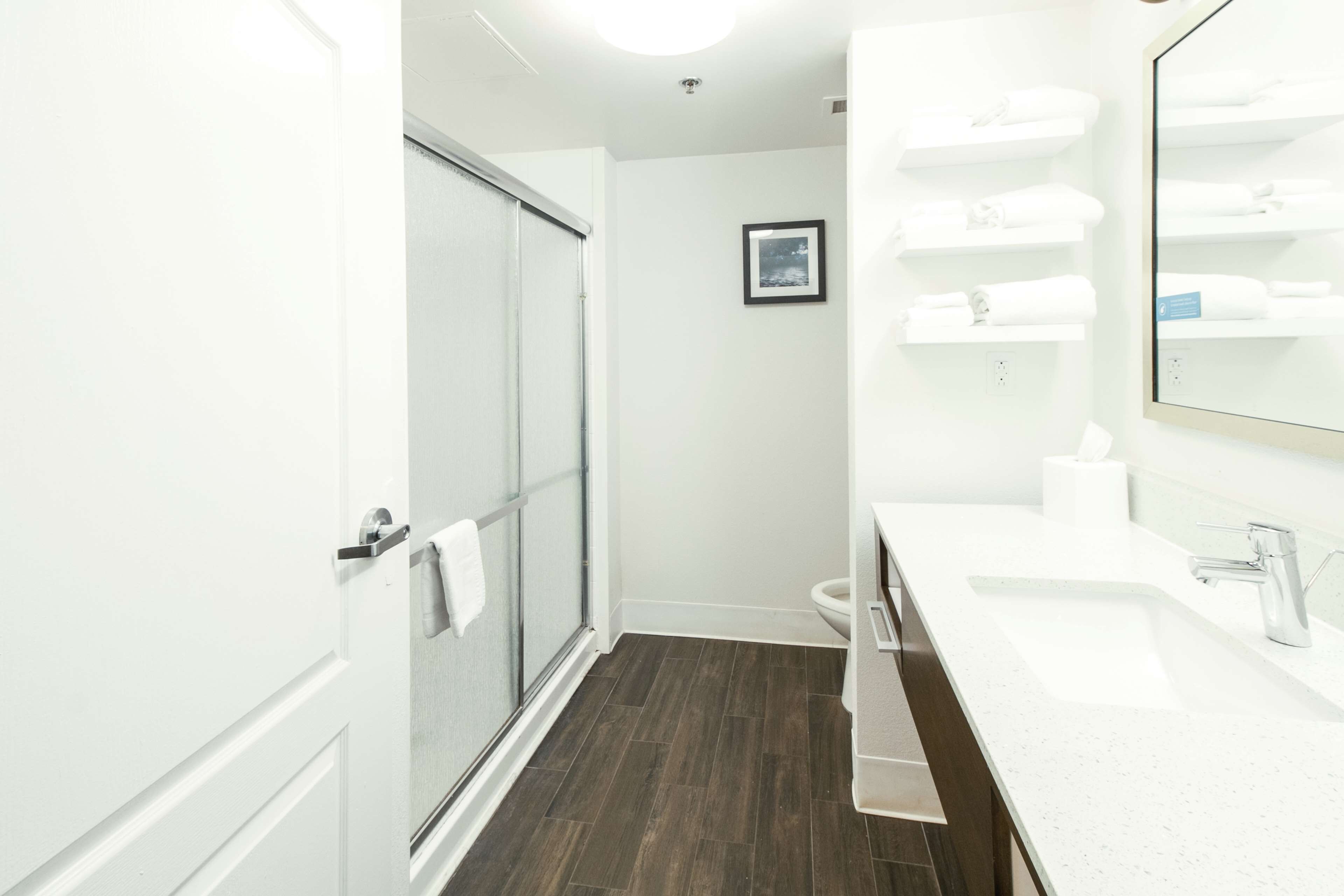 Une salle de bain moderne avec une porte de douche en verre, un lavabo blanc avec un miroir et des toilettes.