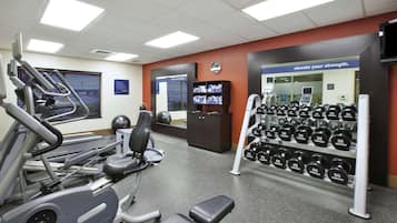 Une salle de sport équipée de tapis de course, d’appareils de musculation et d’une série de haltères.