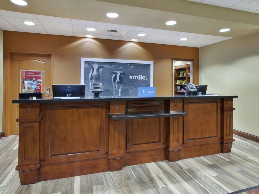 Un mostrador de recepción con detalles de madera, un cartel grande que anuncia una sonrisa y el logotipo de Hilton.