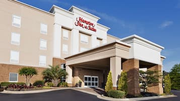 Welcome to Hampton Inn & Suites, featuring a modern design with a red sign and a covered entrance.