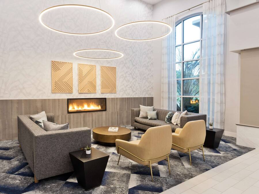 Una sala de estar moderna con chimenea, un ventanal grande y un tapete con diseño geométrico.