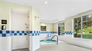 Une salle de bain moderne avec une douche, une petite piscine et un carrelage bleu et blanc à motifs de carreaux.
