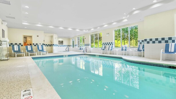 Une grande piscine intérieure dotée de nombreux chaises longues et d’un vestiaire.