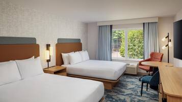 Une chambre d’hôtel avec deux lits, un bureau, une chaise et une télévision.