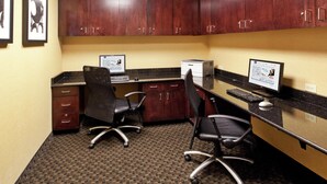 A hotel office with two desks, chairs, and cabinets.