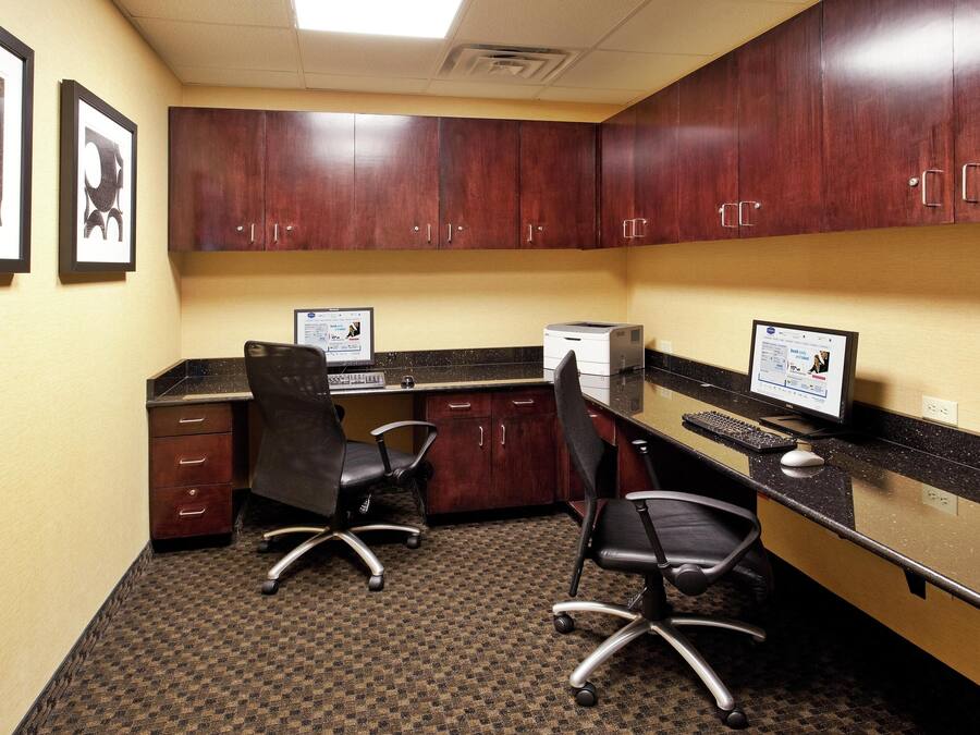A hotel office with two desks, chairs, and cabinets.