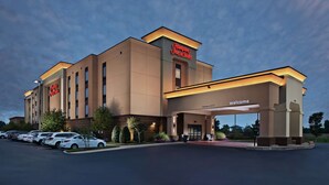 A Hampton Inn Suites hotel with a clear entrance, parking lot, and a sign indicating a clearance of 12'6".