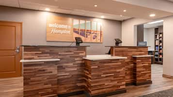 Ein Empfangstresen mit einem 'Welcome to Hampton' Schild, einem Wanddesign aus Holz und Blick auf Gleise.