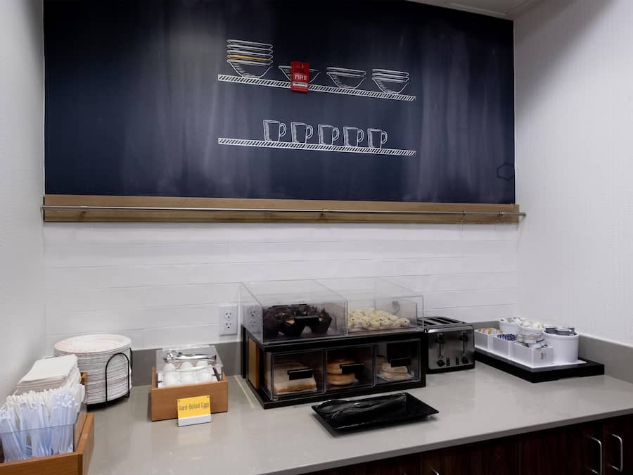 Un área de desayuno con un menú en una pizarra, un tostador y una presentación de huevos duros.