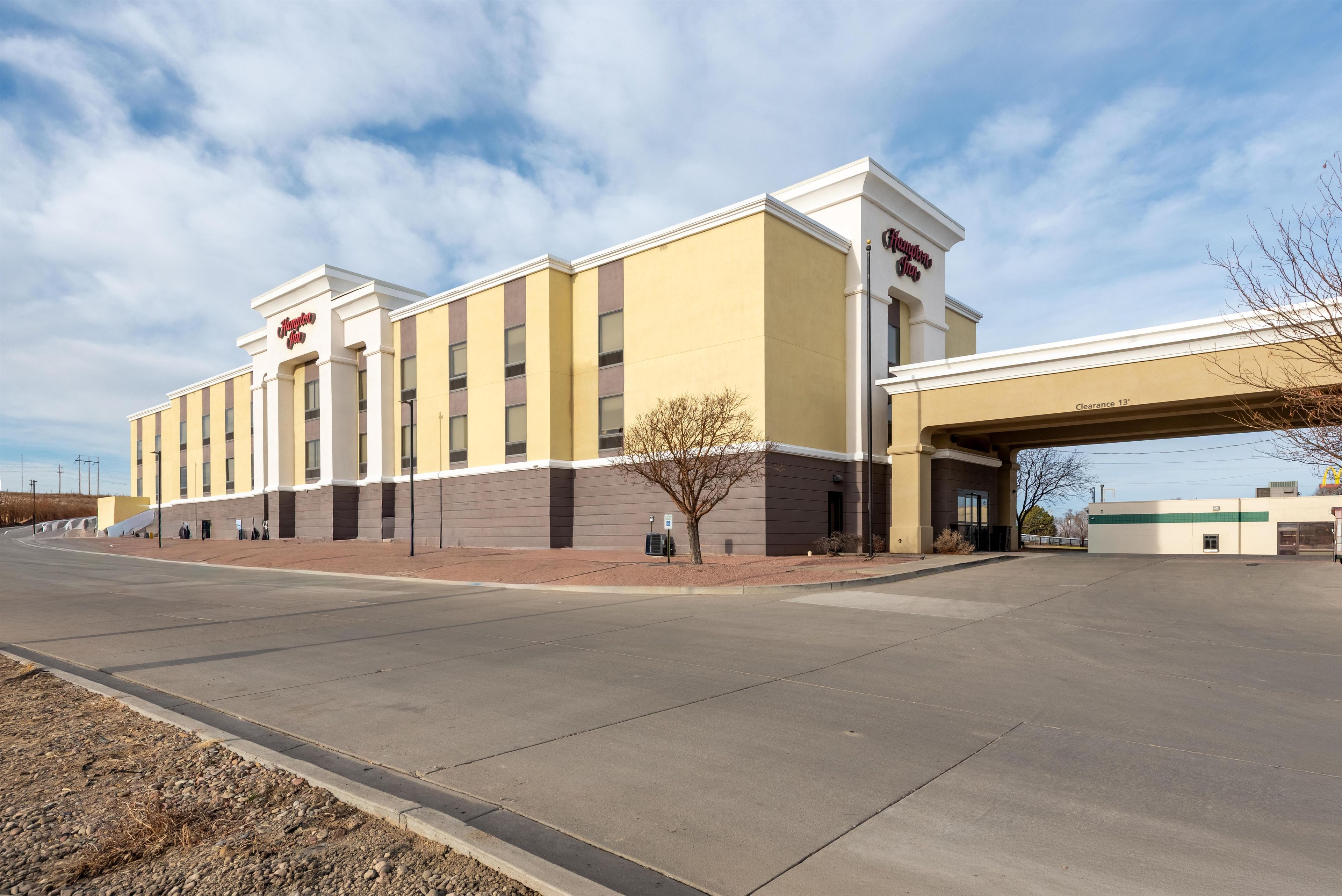 Un hôtel Hampton Inn au design moderne, doté d’un toit plat et d’un grand parking.