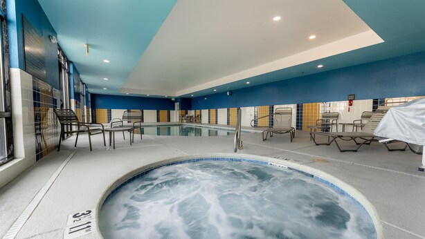 A hot tub with a pool, chairs, and a tiled wall. - Hampton Inn La Junta (La Junta)