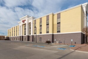 A hotel with a modern facade, multiple parking spaces, and a clear sky. - Hampton Inn La Junta (La Junta)