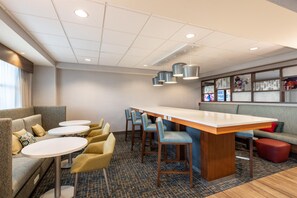 A hotel lobby with a bar area, seating, and a patterned carpet. - Hampton Inn La Junta (La Junta)