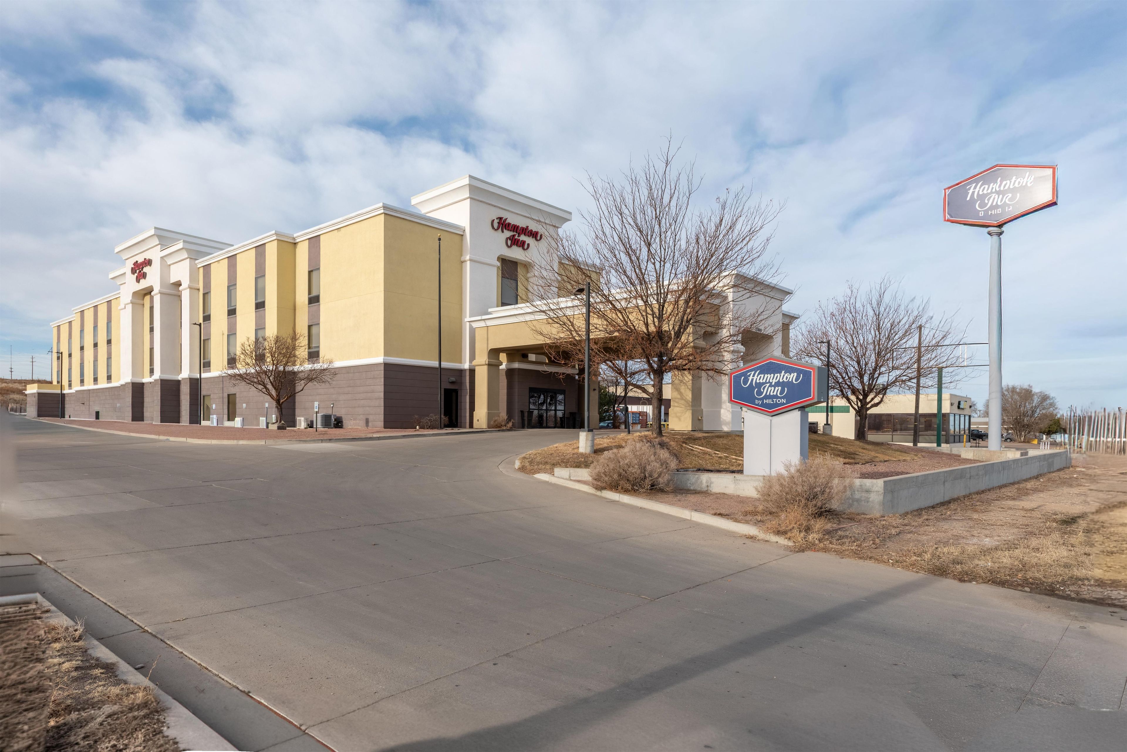 Un hôtel au design moderne, avec une enseigne bien visible indiquant qu’il s’agit d ’un Hampton Inn by Hilton.
