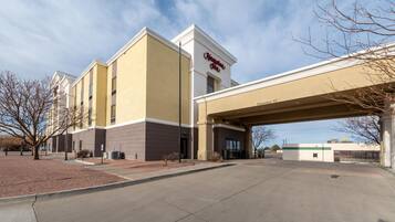 Un hotel Hampton Inn con entrada despejada, estacionamiento techado y un McDonald's enfrente.