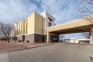 A Hampton Inn hotel with a clear entrance, a covered parking area, and a McDonald's across the street.