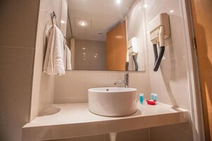 A modern bathroom with a white sink, a mirror, and a towel hanging on the wall.
