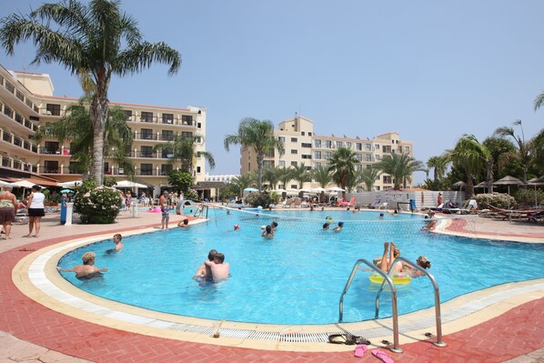 A swimming pool surrounded by palm trees and multi-story buildings with balconies. - Tsokkos Gardens Hotel (Paralimni)