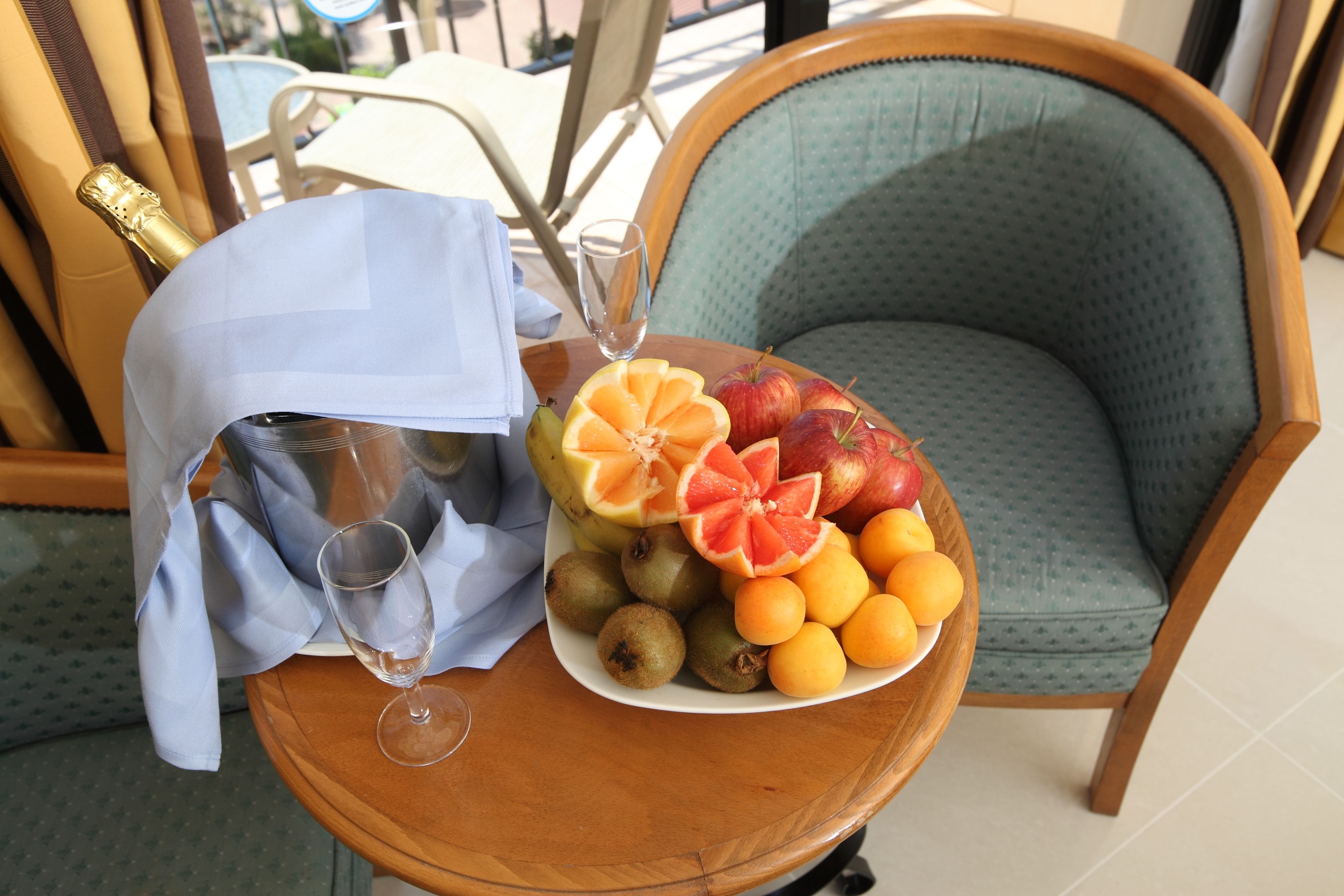 Et bord med et fad frugt, en champagneflaske og et glas.