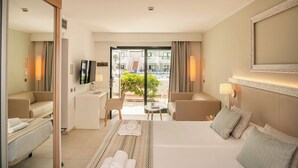 Quarto de hotel com cama, duas poltronas, uma escrivaninha, televisão e vista para a piscina.