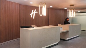 Een modern receptiebalie met een houten achtergrond en een neonbord.