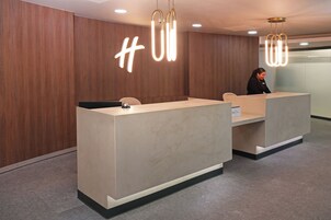 Un mostrador de recepción moderno con un fondo de madera y un letrero de neón.