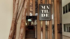 Een moderne entree van een gebouw met een bordje voor 'MATILDE BISTRO'.