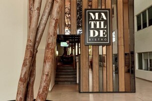 Entrada de un edificio moderno con un cartel que dice 'MATILDE BISTRO'.