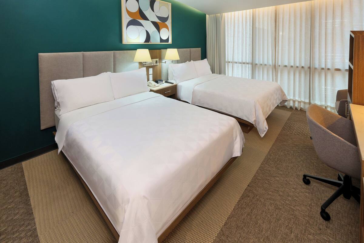 Une chambre d’hôtel avec deux lits, un bureau et une chaise.