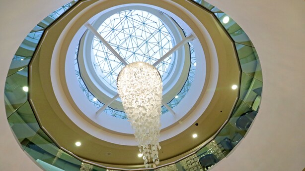 Een meerlaags atrium met een centrale glazen koepel en een hangende kroonluchter.