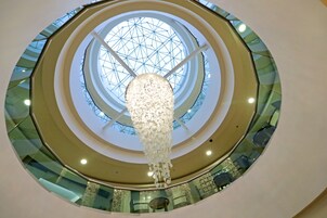Un atrio de varios niveles con una cúpula de cristal central y un candelabro colgante.