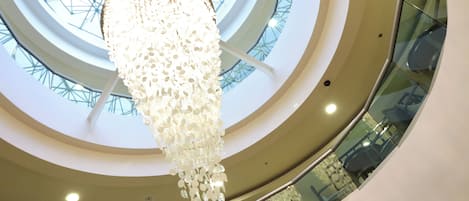 Un intérieur moderne avec un puits de lumière central en verre et un luminaire décoratif suspendu.