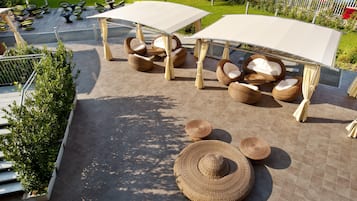 Un patio al aire libre con mobiliario de mimbre y sombrillas grandes.