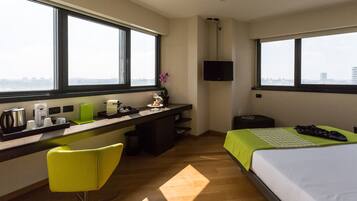 A hotel room with a desk, a chair, a bed, and a TV.