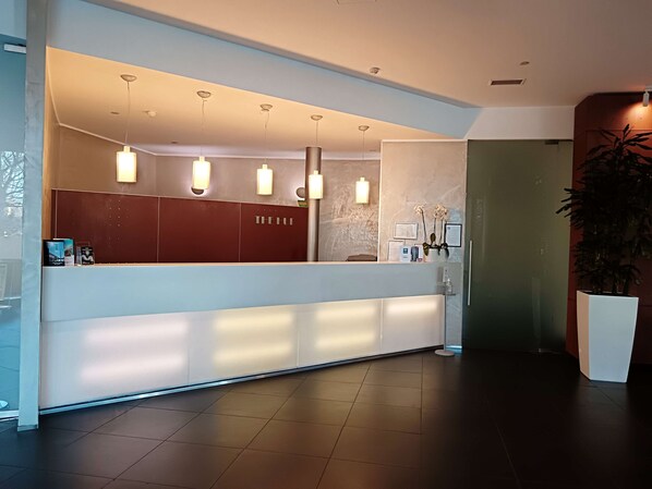 A reception area with a modern design, featuring a reception desk, pendant lighting, and a potted plant. - Best Western Plus The Hub Hotel (Milan)