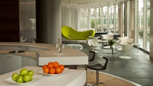 Un intérieur moderne comprenant un coin cuisine, un espace repas avec une table et des chaises blanches, ainsi qu’une chaise vert vif.