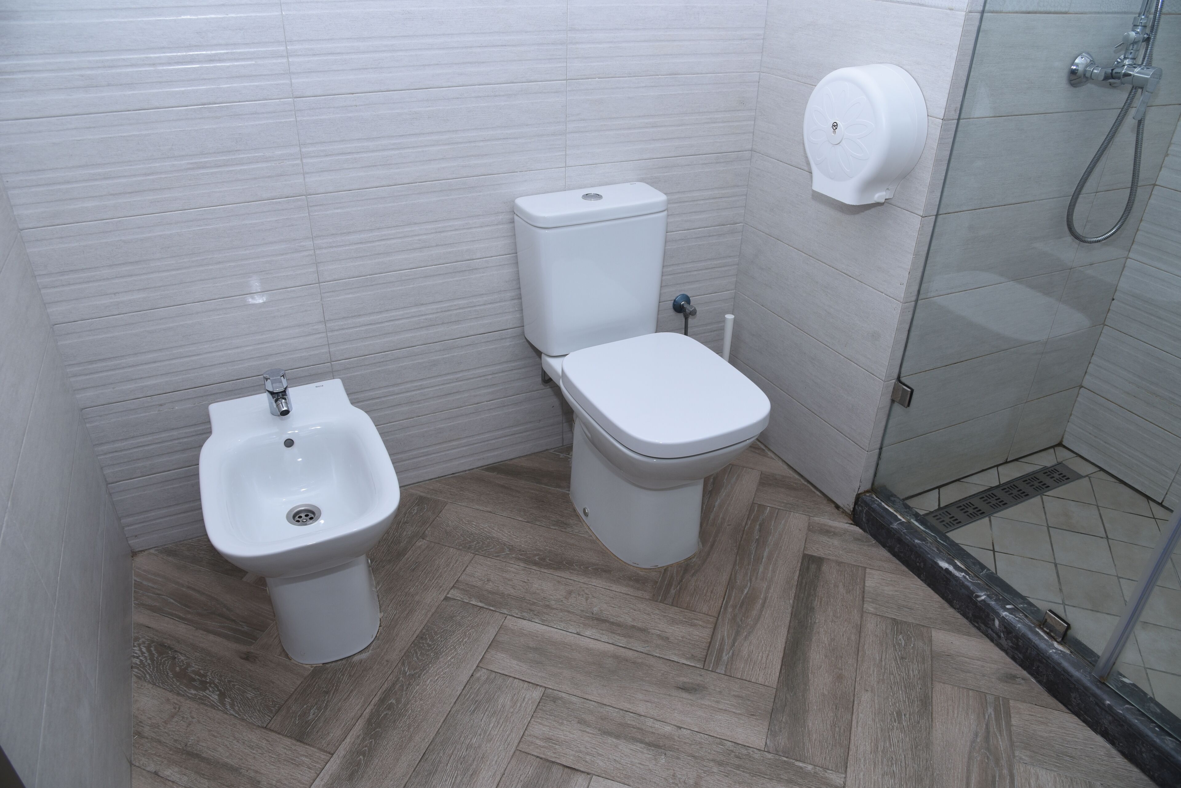 A bathroom with a bidet, toilet, and a hand dryer.