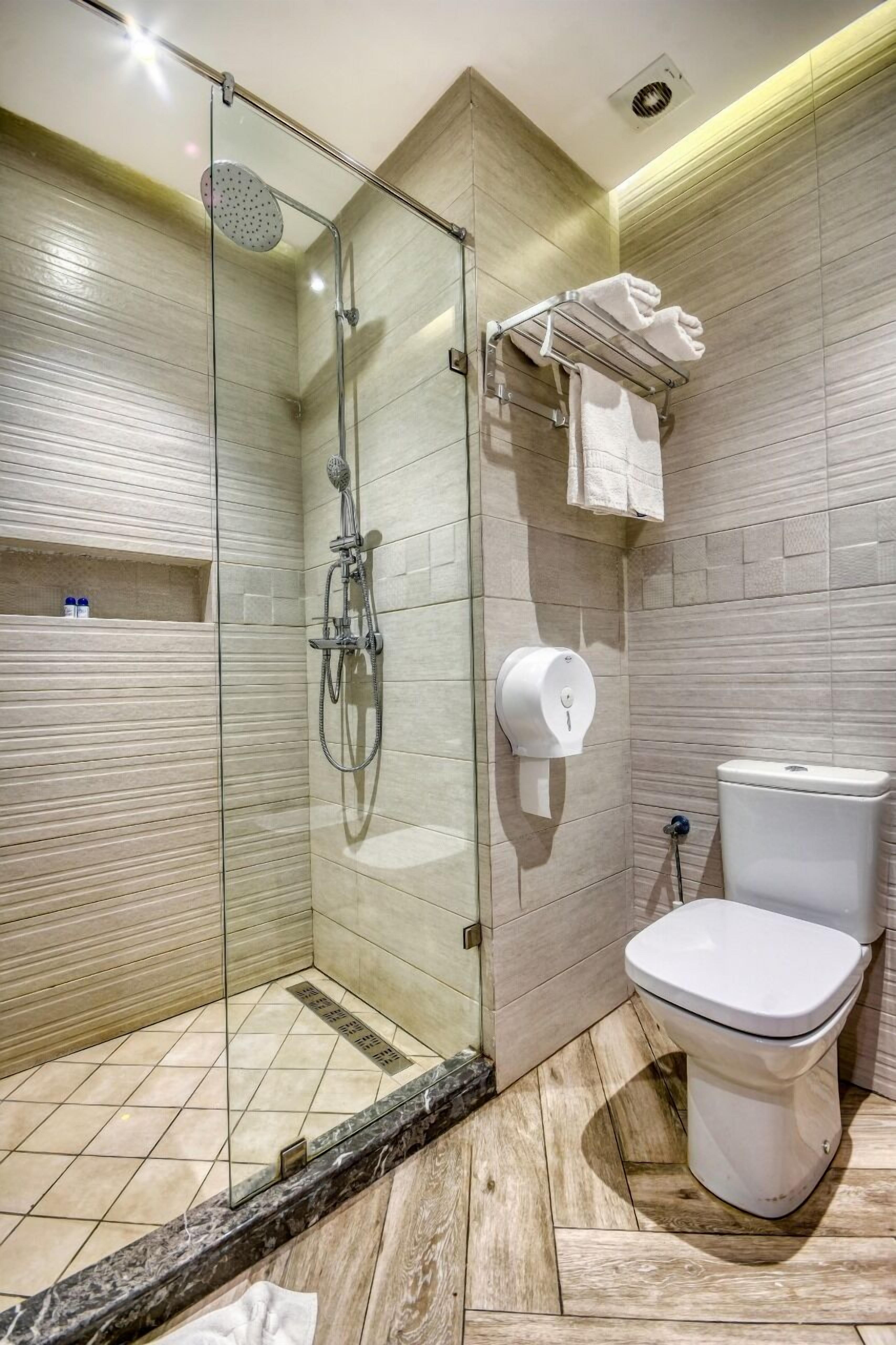 Un baño moderno con ducha de vidrio, inodoro y barra para toallas.