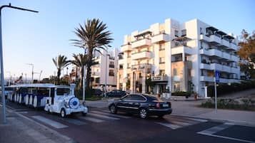 A multi-story building with balconies and a car parked in front.