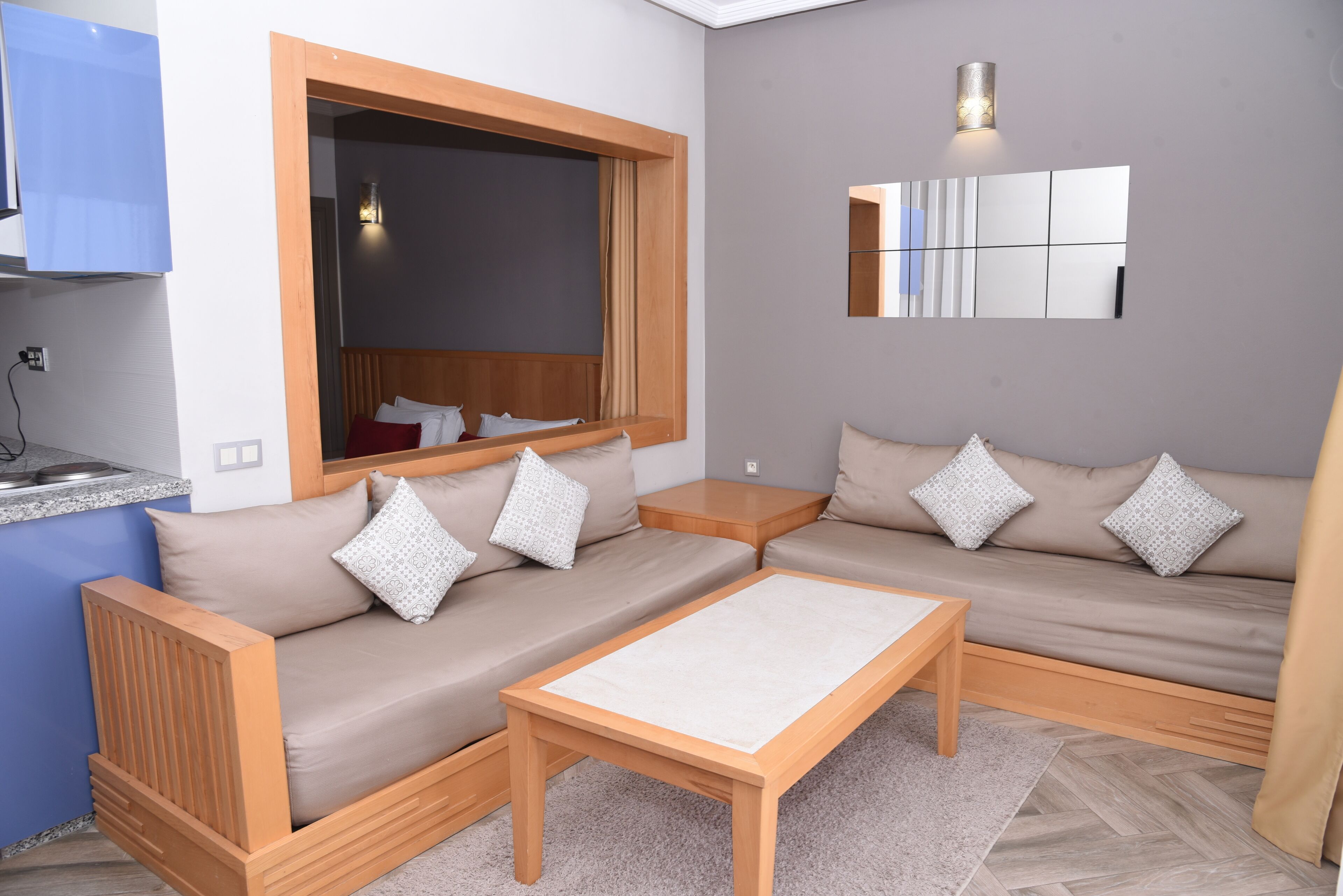 Una sala de estar moderna con un conjunto de sofás, una mesa de centro, una ventana y una zona de cocina.